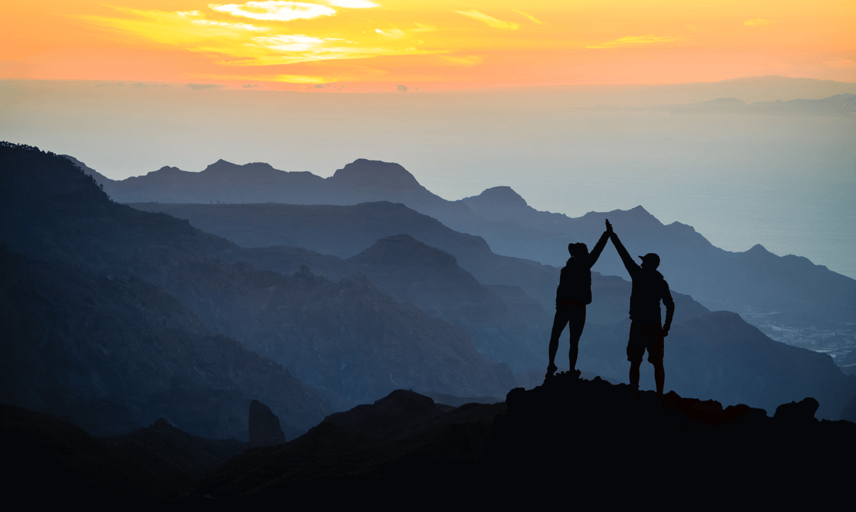 Two people on a mountain top giving high fives