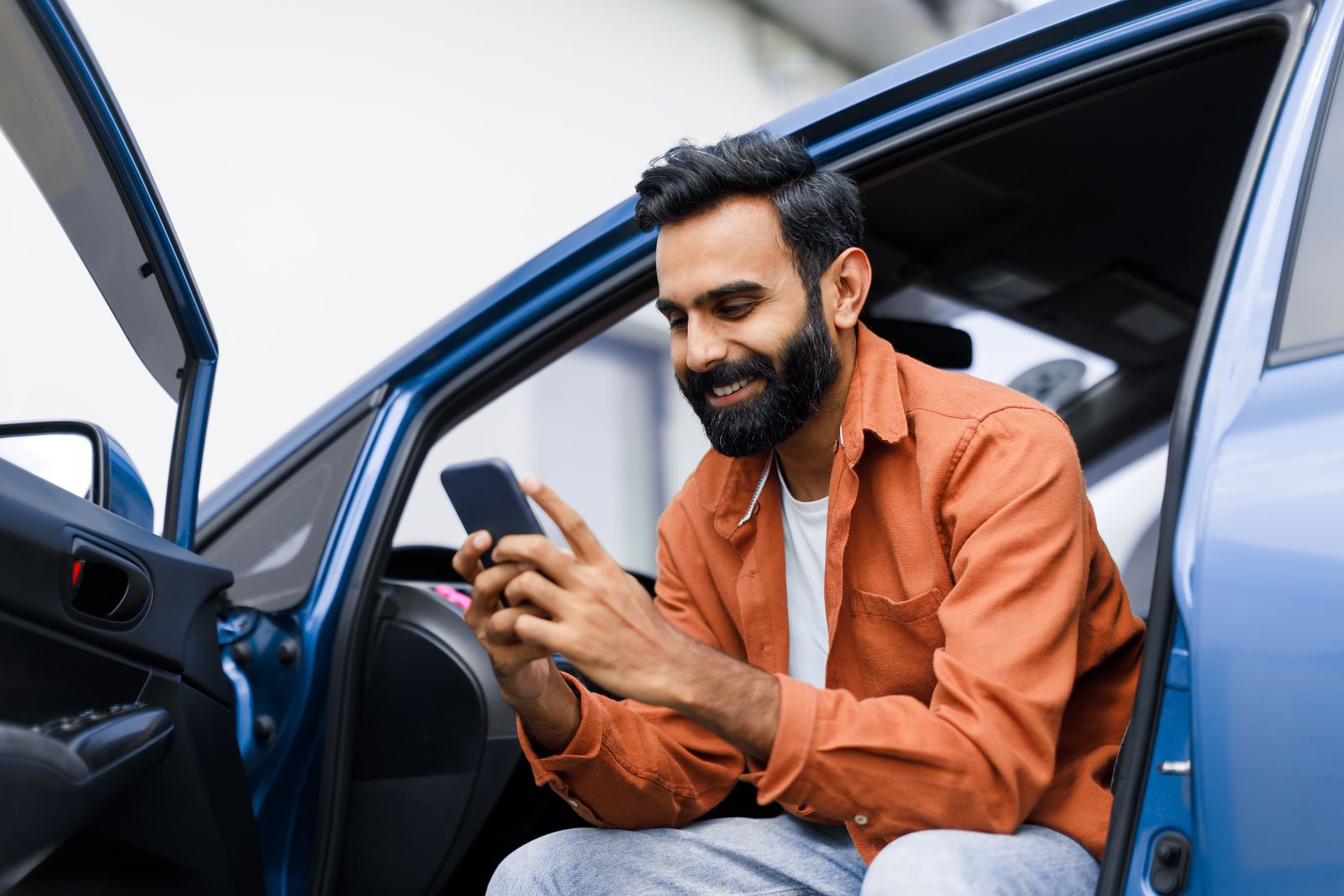 Man looking at car insurance outside of his car.